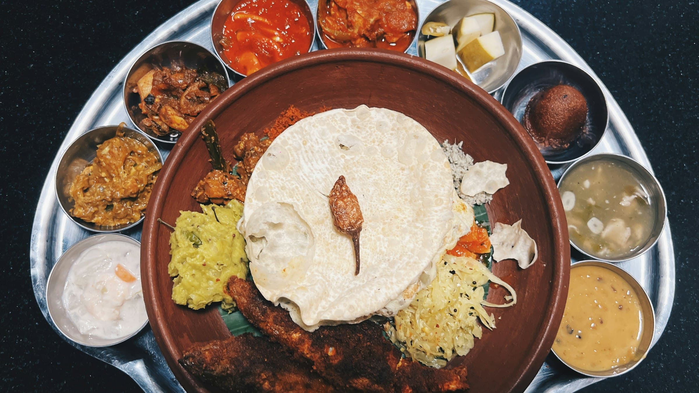 South Indian meals served on a banana leaf with rice, sambar, rasam, poriyal, curry, pickle and papad