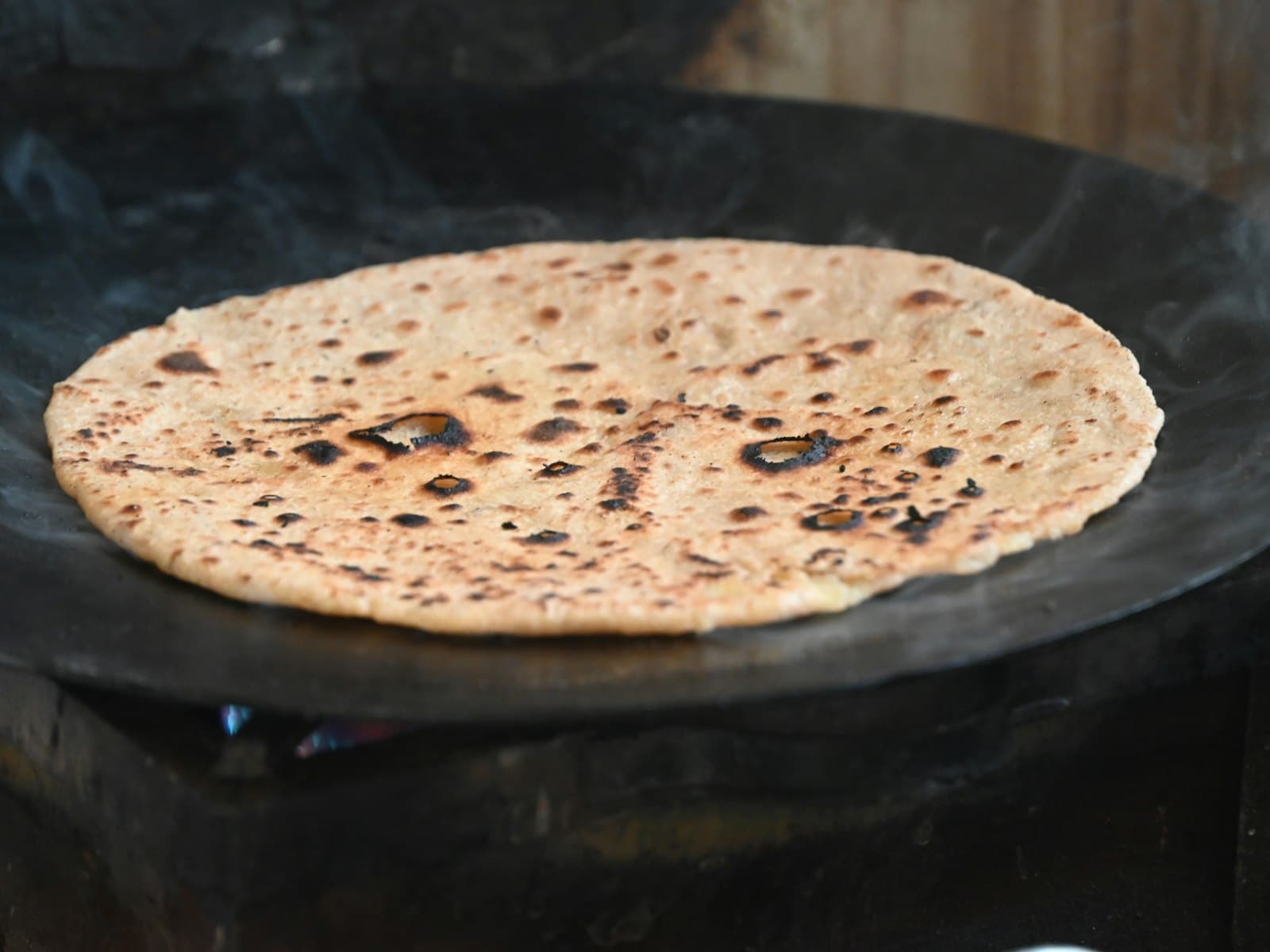 Dosa being cooked on a hot cast-iron tawa