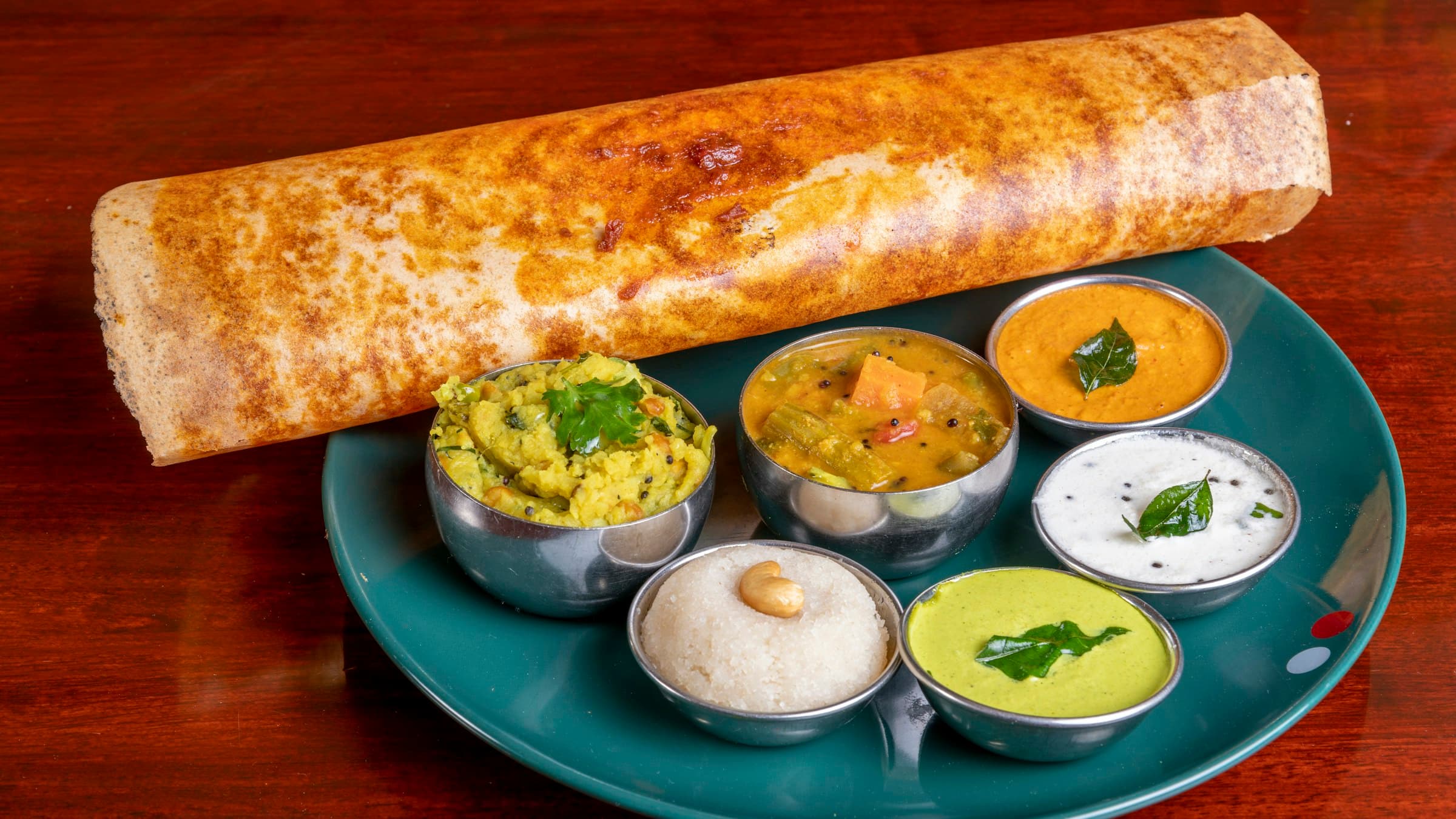 Traditional Tamil food spread on banana leaf — masala dosa, chicken biryani, sambar, chutneys and filter coffee